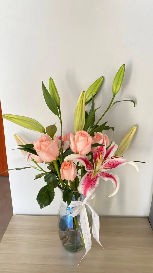Arreglo de lirios y rosas en florero de vidrio