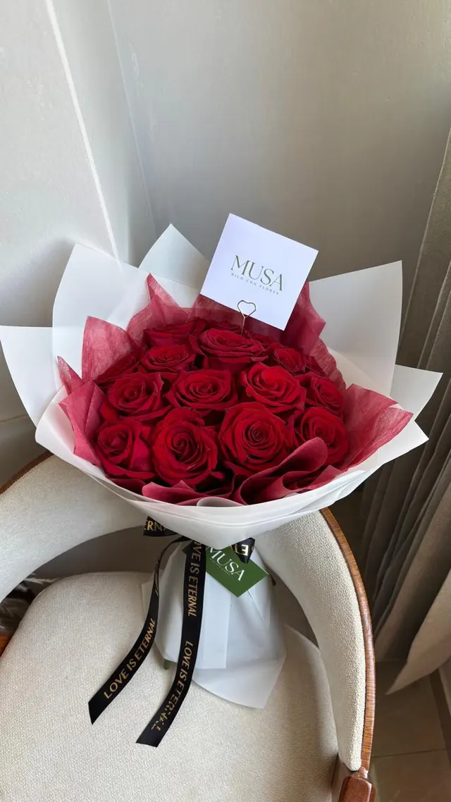 Ramo de rosas rojas en papel blanco con cinta negra